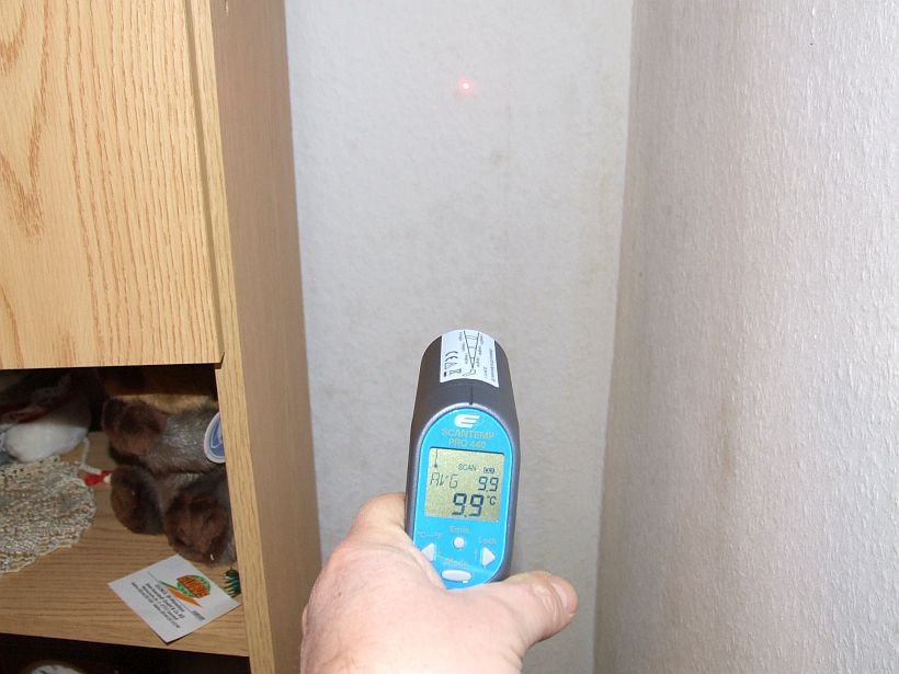 Mit einem Infrarotthermometer wird die Oberflächentemperatur in einer Außenwandecke gemessen Mit einem Infrarotthermometer wird die Oberflächentemperatur in einer Außenwandecke gemessen
